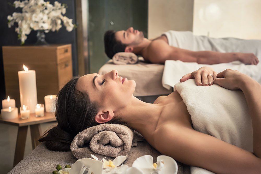 A couple enjoying a relaxing treatment at a spa, decorated with candles.