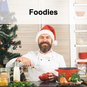 Man with a beard wearing a chef's apron and a Christmas hat in the kitchen.