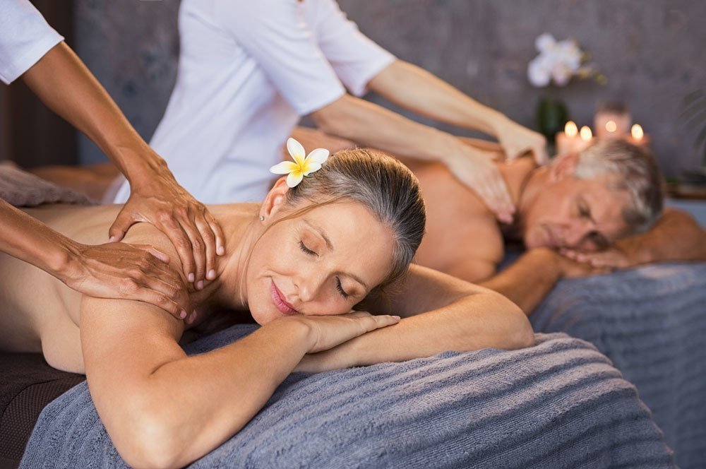 Older couple enjoying a couples' massage treatment in a spa.